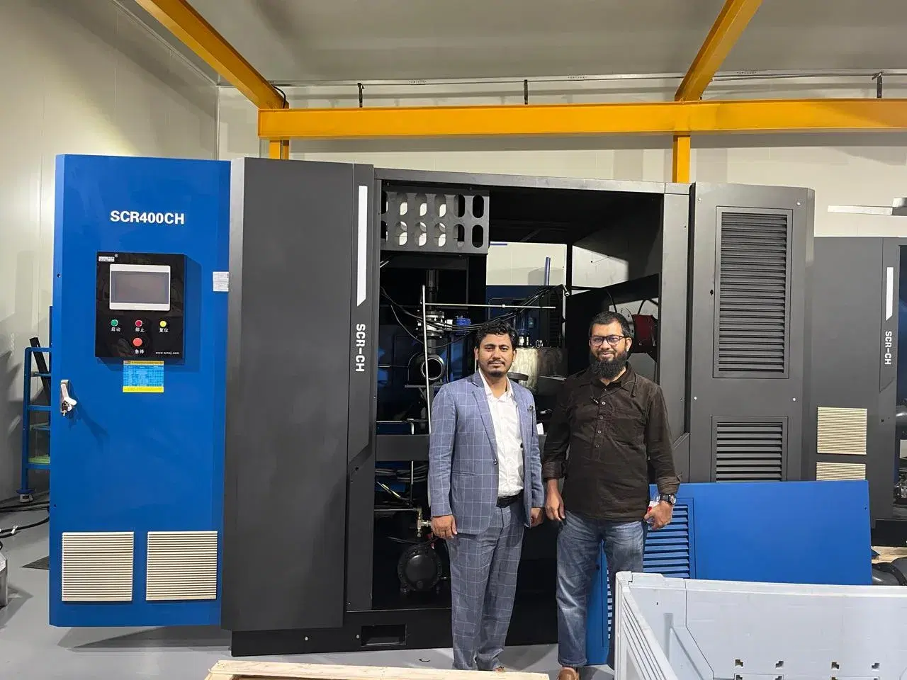 Innovation Nexus engineers beside an SCR400CH screw air compressor during a factory visit